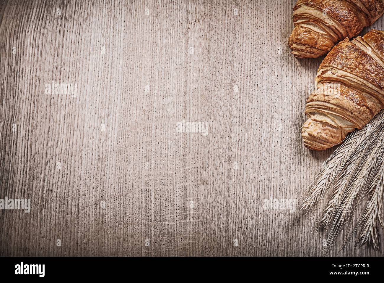 Orecchie di segale di frumento dorato croissant su un copyspace di legno Foto Stock