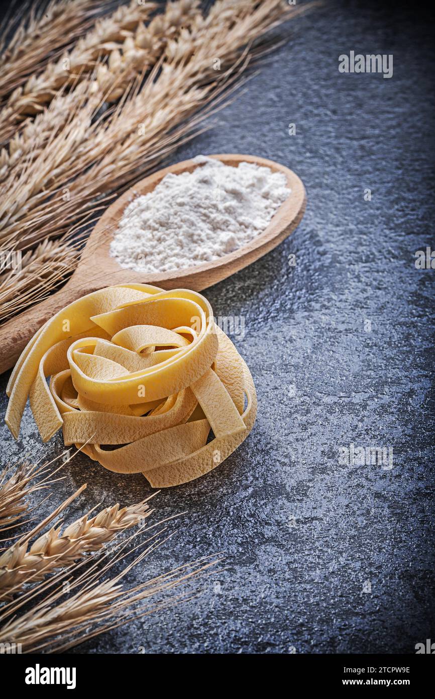 Spighe di segale di grano dorato farina di cucchiaio di legno pasta cruda su fondo nero concetto di cibo e bevande Foto Stock