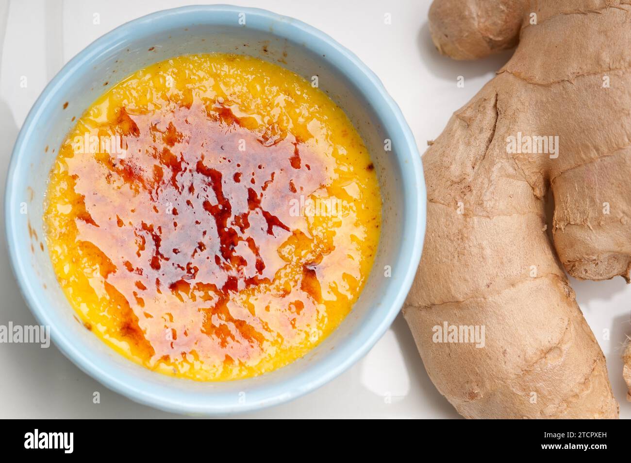 Dessert macro brulee con crema di zenzero fresco e radici di zenzero crude Foto Stock