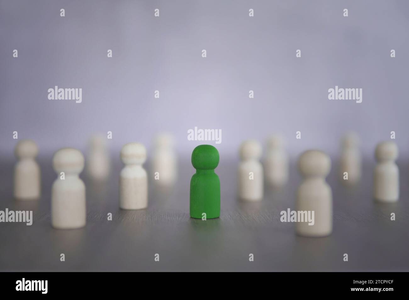 Bambole di legno verde circondate da bambole bianche. Distinguiti dal concetto di massa. Foto Stock