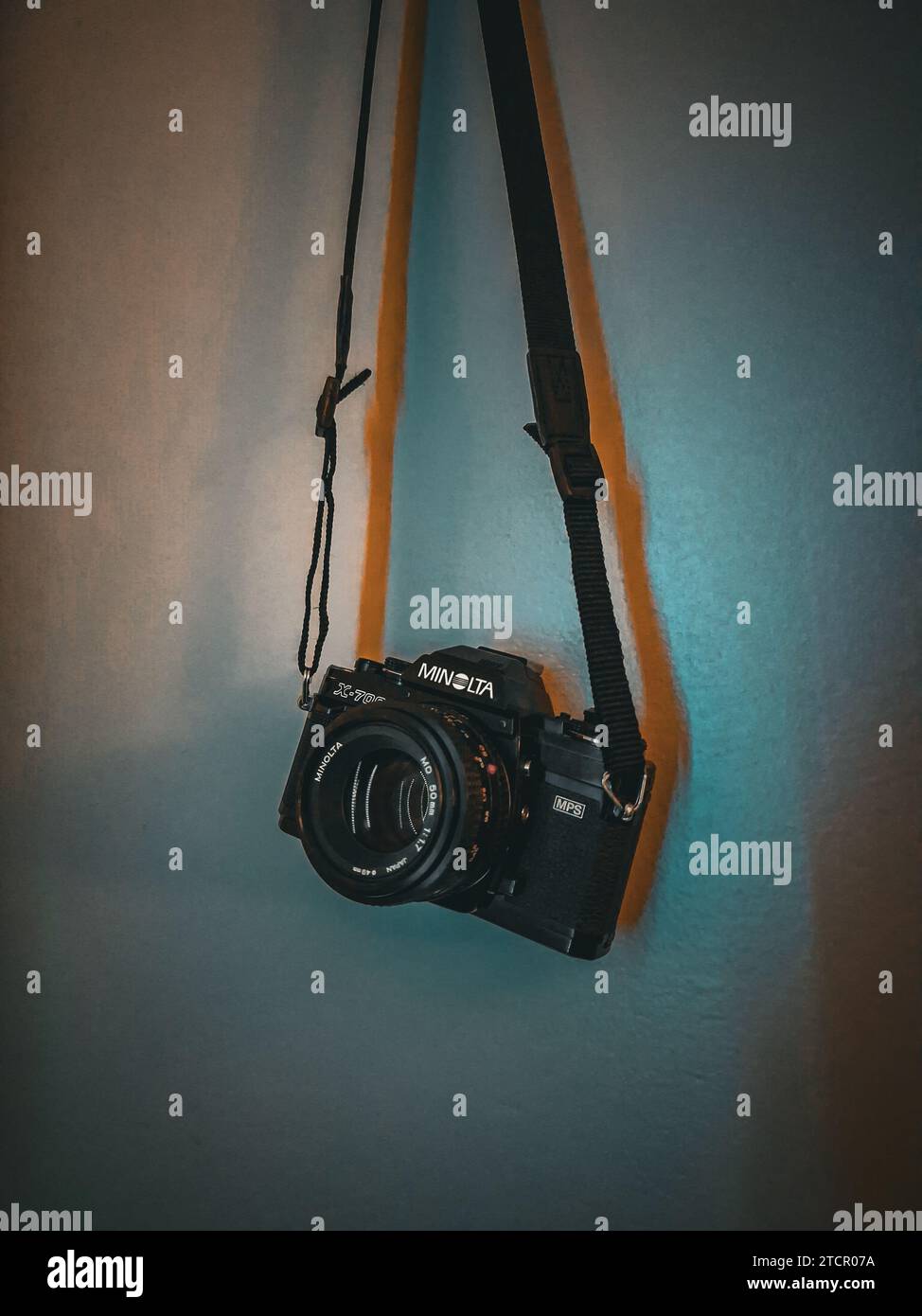 Una cinghia per fotocamera è appesa alla parete e fissata a una fotocamera Foto Stock