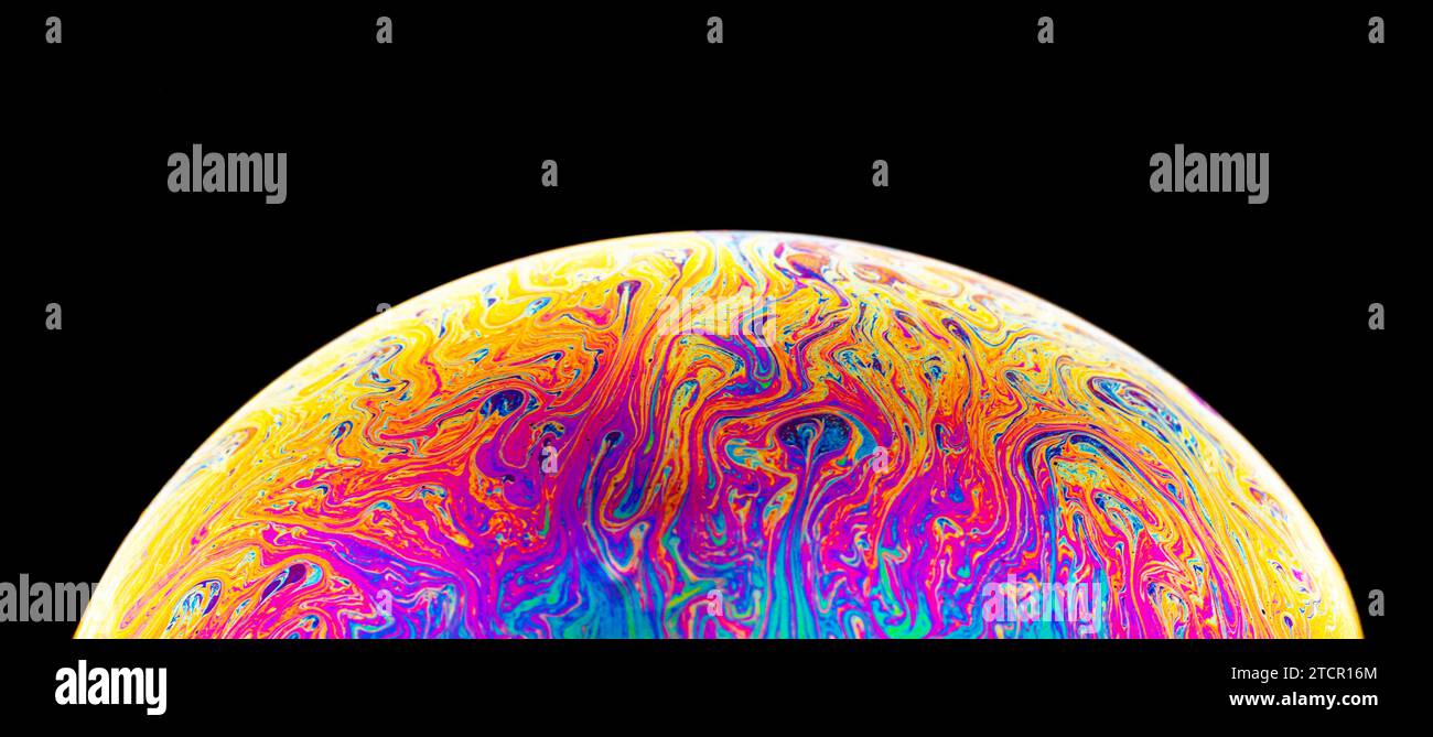 Bolla di sapone arcobaleno su sfondo scuro. Primo piano di una superficie colorata. Colori psichedelici Foto Stock