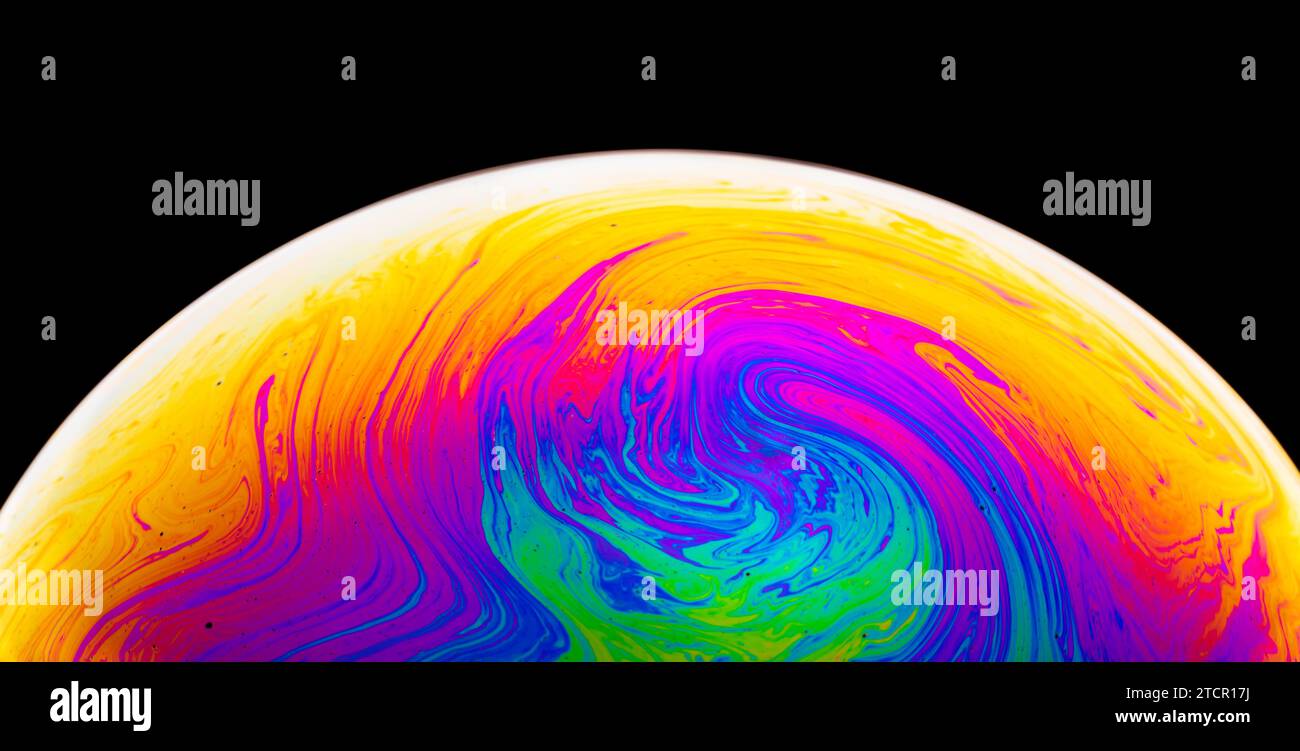Bolla di sapone arcobaleno su sfondo scuro. Primo piano di una superficie colorata. Colori psichedelici Foto Stock