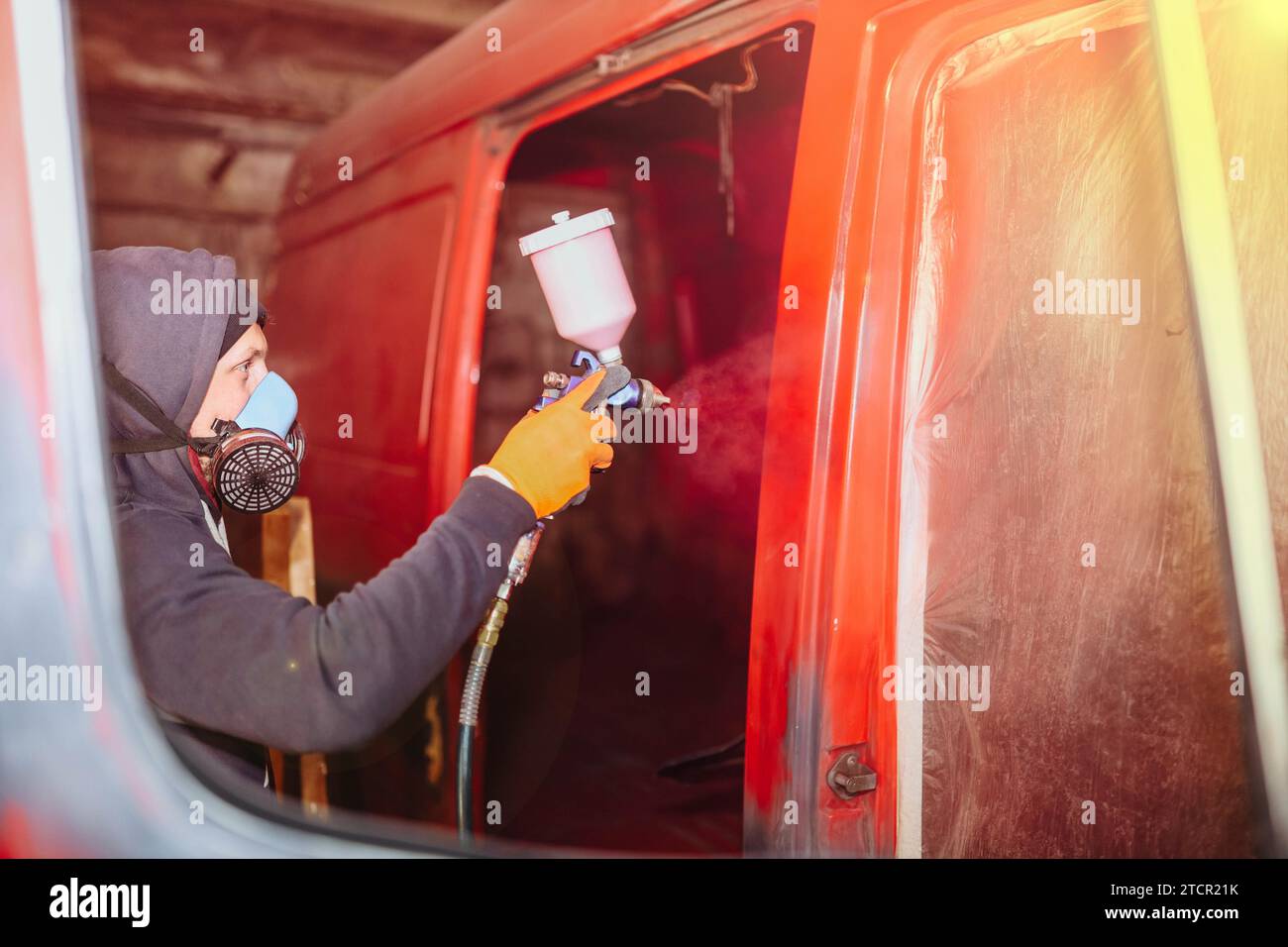 Verniciatura a spruzzo di un furgone rosso. Restauro e riparazione carrozzeria di automobili Foto Stock