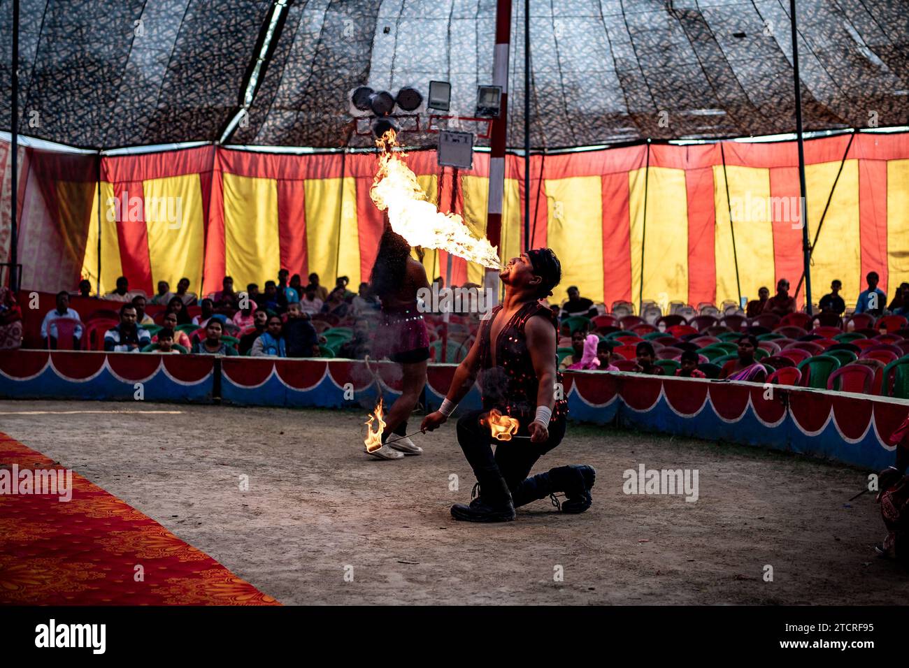 Kolkata, India. 14 dicembre 2023. Un interprete mostra un fuoco-stunts all'interno di una tenda da circo a Calcutta. L'inverno e l'infanzia significavano un periodo in cui c'era un'attrazione e un amore distinti per il circo. Ma ora i tempi sono cambiati, quindi anche la domanda è diminuita, soprattutto dopo che lo spettacolo di qualsiasi tipo di animale nel circo si è fermato, i proprietari delle squadre del circo sono più sconvolti. Ora il gioco è mostrato solo con jolly o persone. E di conseguenza il reddito è diminuito. Ora anche i più piccoli hanno perso interesse per il circo. Credito: SOPA Images Limited/Alamy Live News Foto Stock