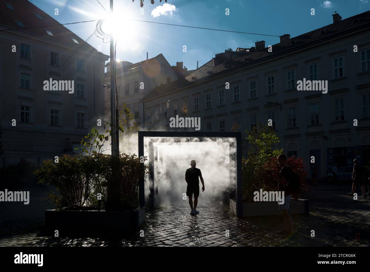 Persona che cammina attraverso il cancello degli sprinkler dell'acqua Foto Stock