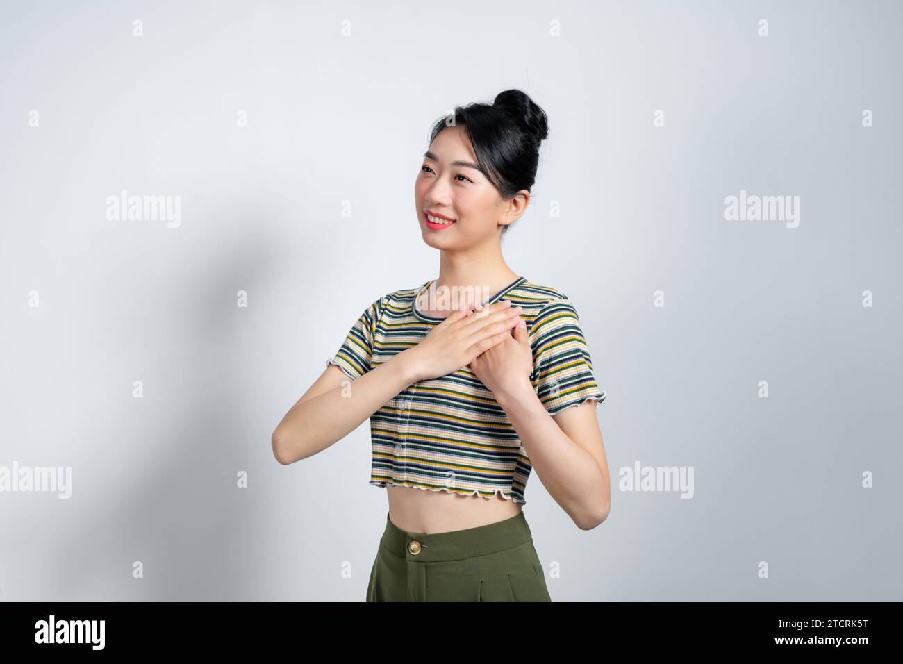 Toccata, tenera e sorridente donna asiatica, felice di ricevere lodi, di tenere le mani sul cuore e di sorridere grata, Foto Stock
