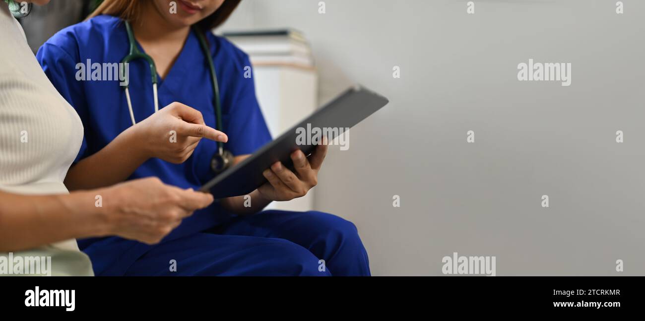 Medico femminile che mostra compressa digitale con i risultati di alcuni test medici per paziente anziano donna Foto Stock