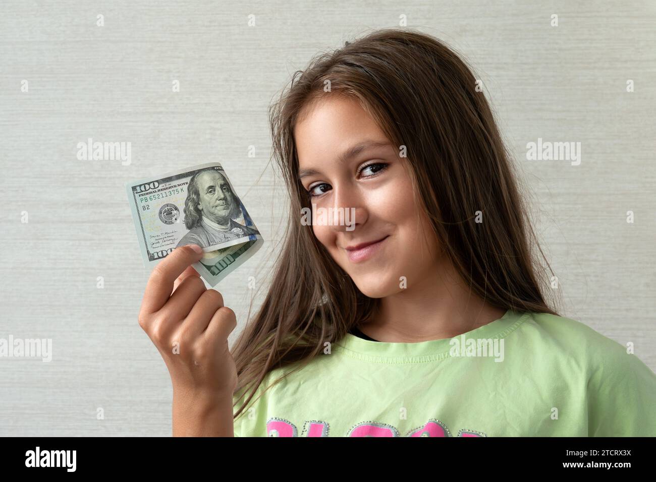 concetto di persone - adolescente sorridente in pullover che detiene centinaia di banconote in denaro da dollari su sfondo grigio Foto Stock