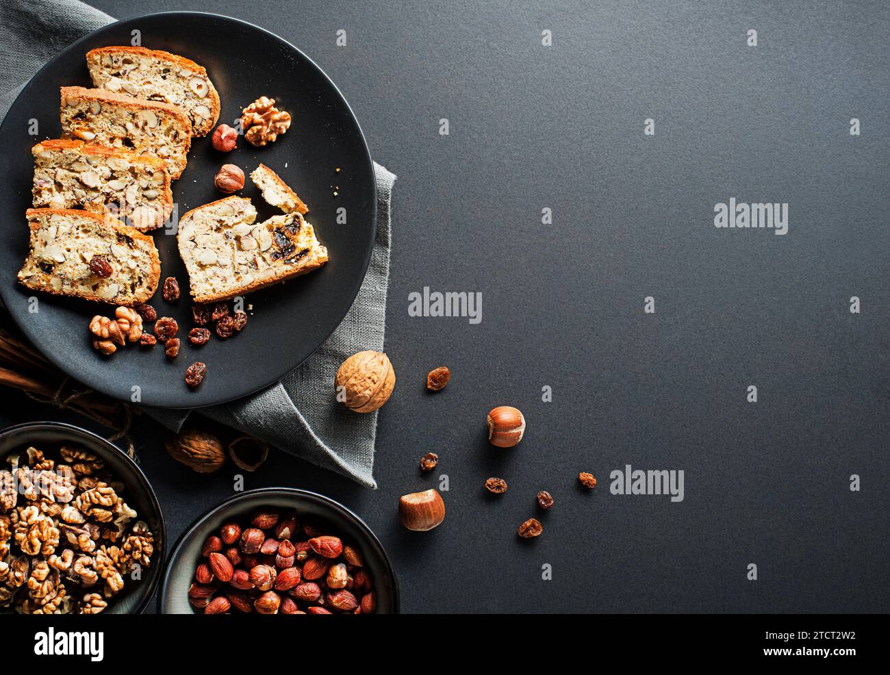 Gustosi biscotti tradizionali fatti in casa su sfondo nero da tavolo. Deliziosi biscotti cantucci con noci e uva passa. Foto Stock
