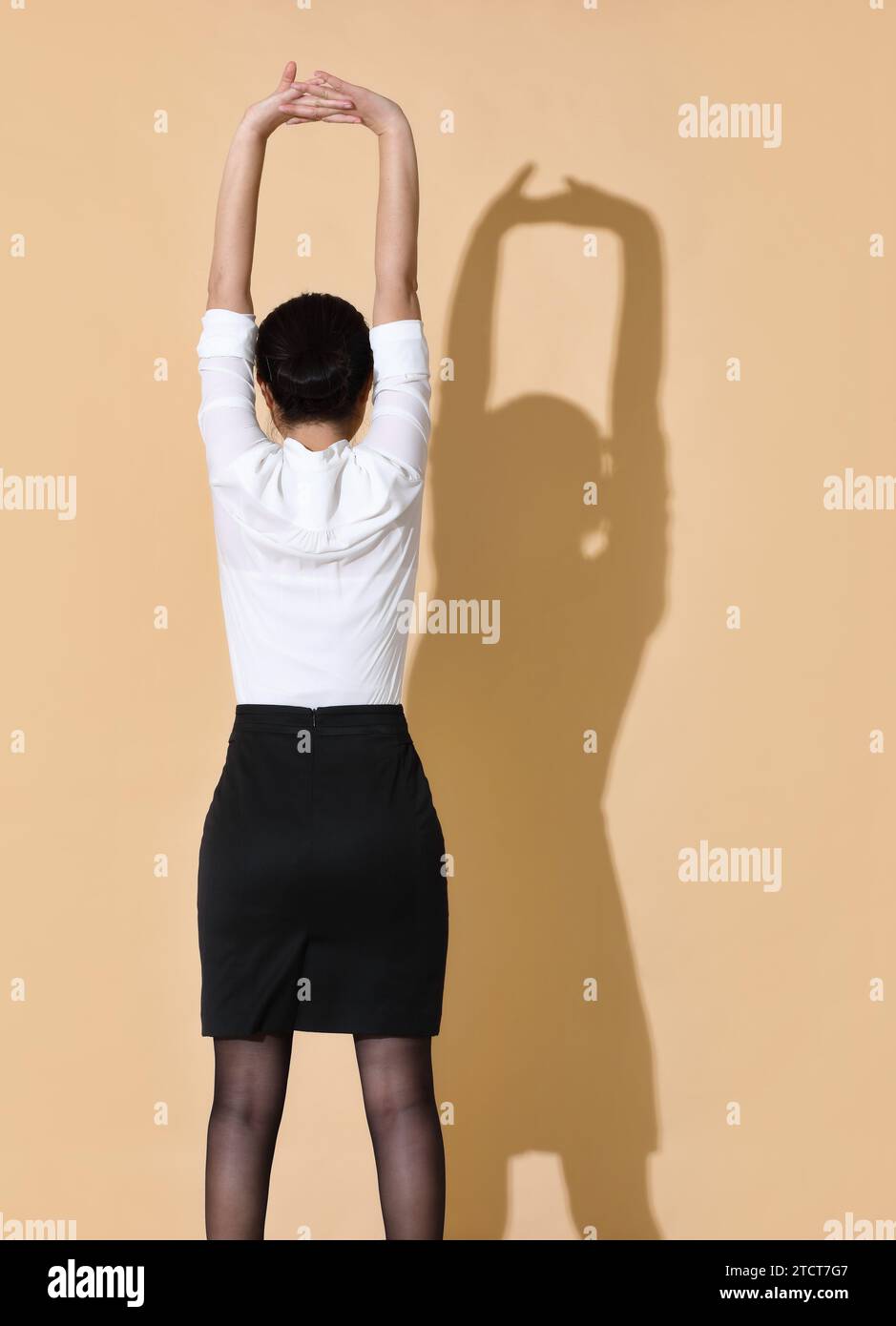 Una donna sta guardando un muro beige e si sta allungando Foto Stock