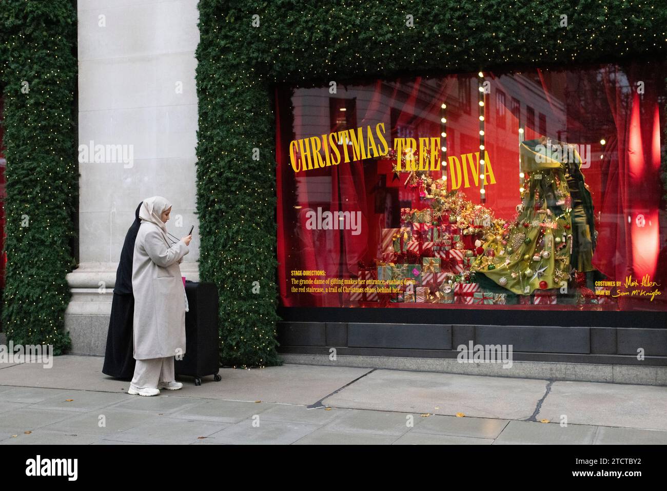 I turisti di Natale si divertono nei grandi magazzini di lusso Selfridges su Oxford Street, vetrina natalizia natalizia, nel centro di Londra, in Inghilterra, nel Regno Unito Foto Stock