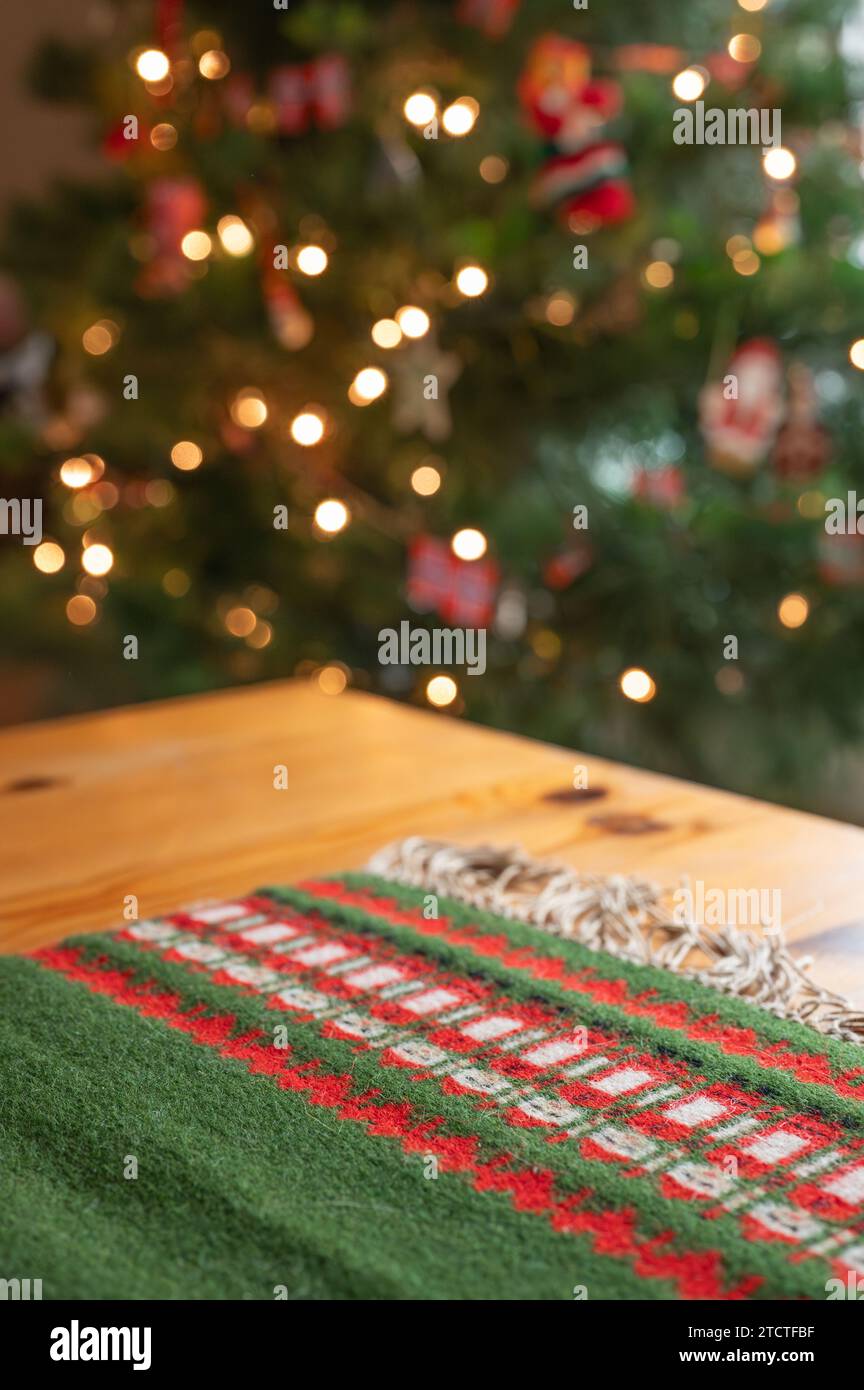 Un tavolino di Natale fatto a mano su un vecchio tavolino di pino con un albero di Natale decorato sullo sfondo. Foto Stock