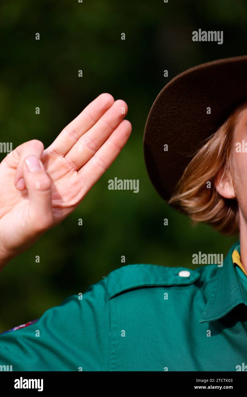 Il boy scout in uniforme esegue un saluto di tre dita. Gesto della mano del simbolo scout. Francia. Foto Stock