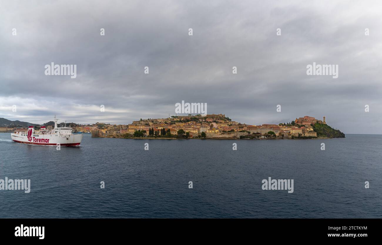 Portoferraio, Italia - 12 novembre 2023: Traghetto per Toremar in partenza dall'Isola d'Elba con il centro storico di Portoferraio e il porto sullo sfondo Foto Stock