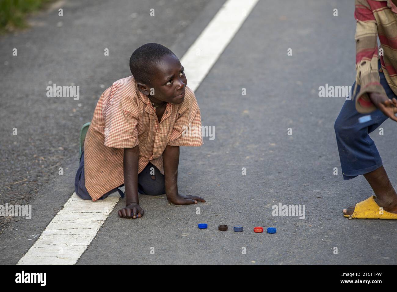 Ragazzi che giocano con i tappi di plastica su una strada vicino a Karongi, in Ruanda Foto Stock