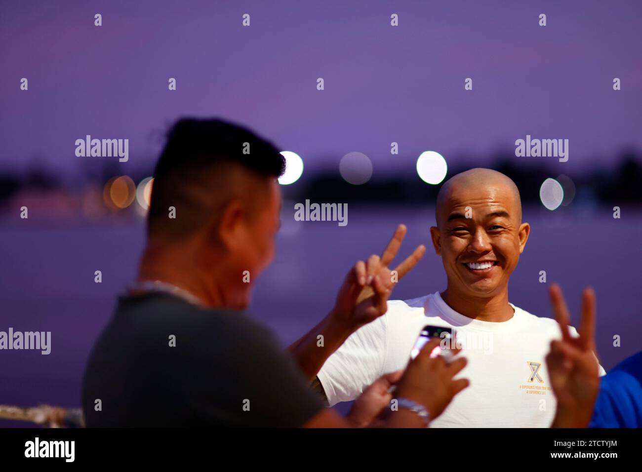 Traghetto per auto sul fiume Mekong vicino a Chau Doc. Uomini sorridenti al tramonto che fanno foto. Foto Stock
