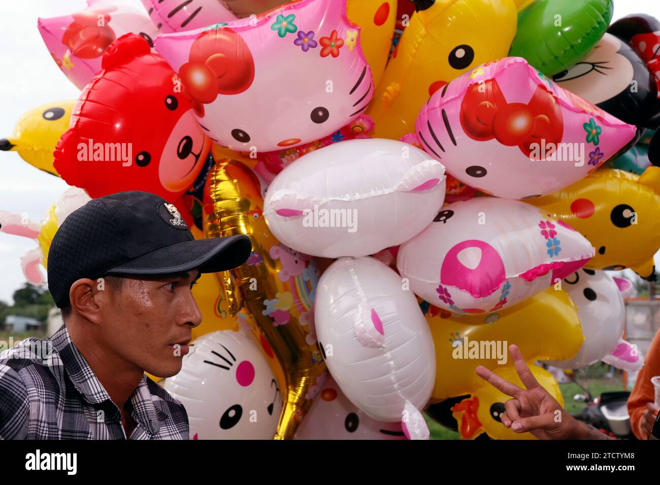 Scena di strada con un fornitore locale che trasporta un mucchio di palloncini colorati. Foto Stock