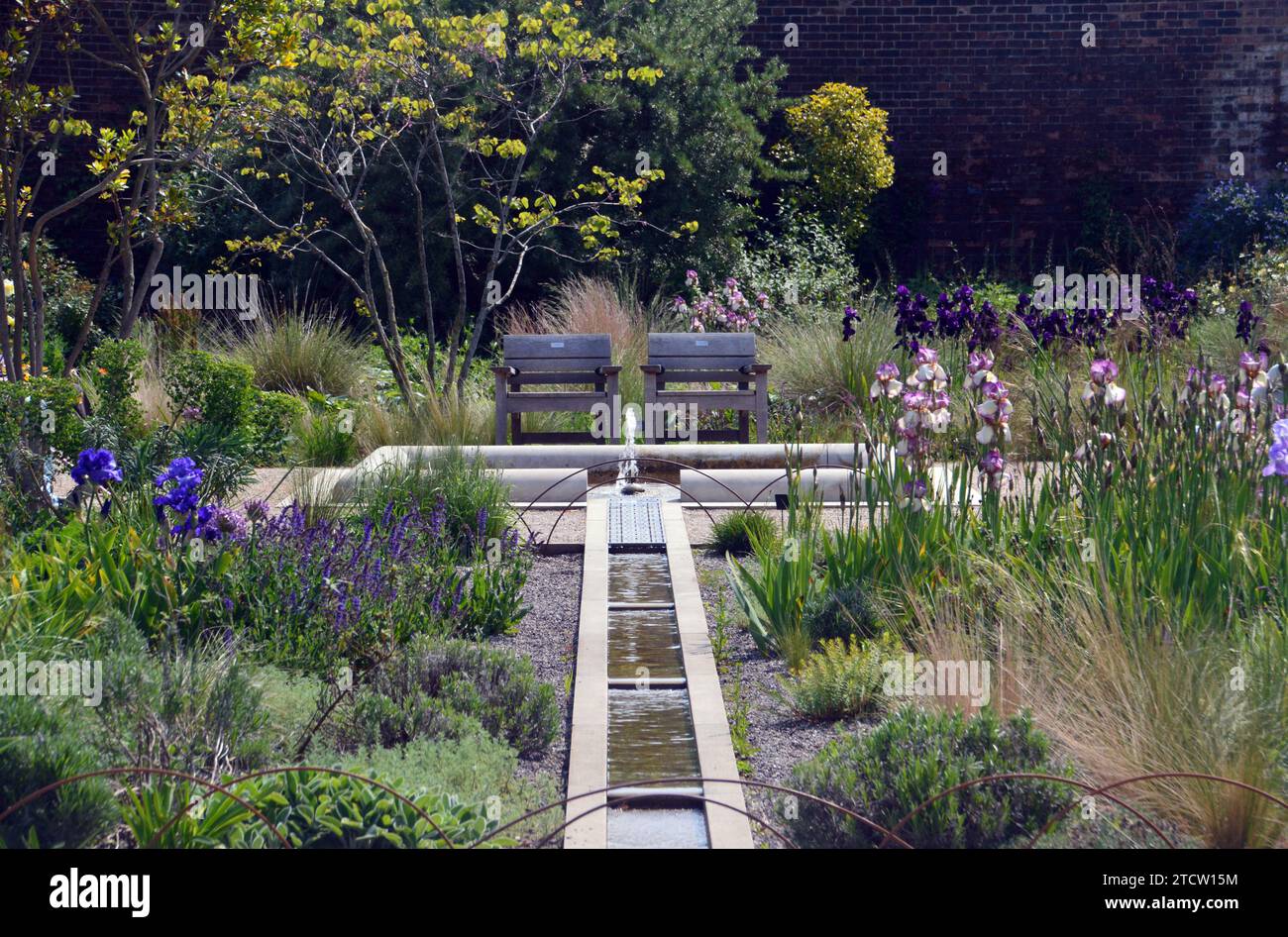 Posti a sedere e fontana dal canale dell'acqua da uno stagno nel Victorian Weston Walled Paradise Garden al RHS Garden Bridgewater, Worsley, Manchester, Regno Unito. Foto Stock