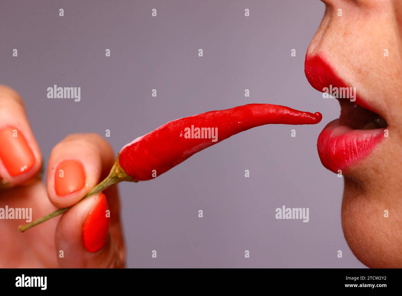 Donna che mangia peperoncino rosso piccante. Primo piano. Foto Stock