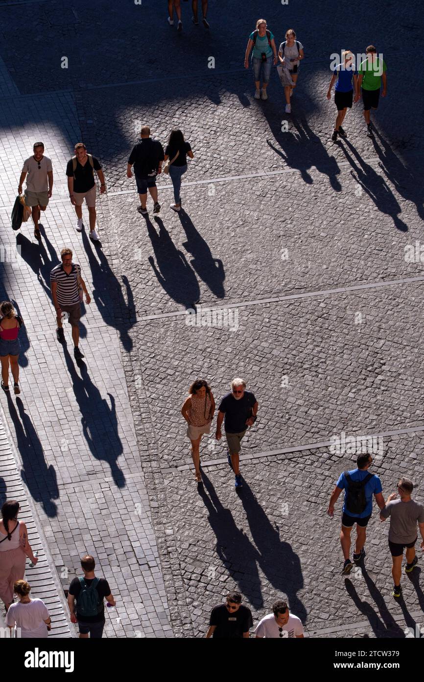 I turisti passeggiano in una piazza alla luce del sole, Roma, Italia Foto Stock