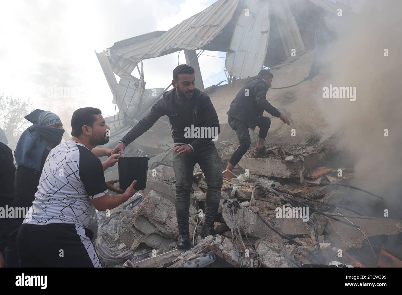 I soccorritori e i civili cercano i sopravvissuti tra le macerie di edifici distrutti a seguito del bombardamento israeliano i soccorritori e i civili cercano i sopravvissuti tra le macerie di edifici distrutti a seguito del bombardamento israeliano a Rafah, nella Striscia di Gaza meridionale il 14 dicembre 2023, migliaia di civili palestinesi sono morti dal 7 ottobre, 2023, dopo che i militanti palestinesi di Hamas con base nella Striscia di Gaza sono entrati nel sud di Israele in un attacco senza precedenti che ha innescato una guerra dichiarata da Israele ad Hamas con bombardamenti di rappresaglia su Gaza. Foto di Bashar Taleb apaimages Rafah Gaza Strip Palestinian Foto Stock