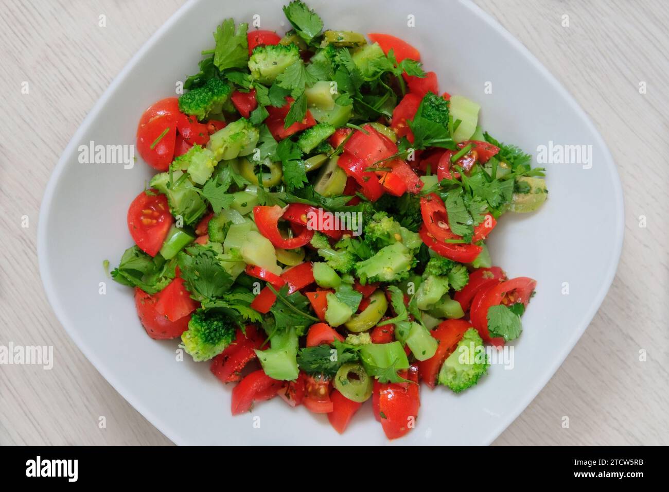 Pomodori, broccoli e altre verdure un piatto bianco su sfondo beige. Insalata di verdure fresche in ciotola. Foto Stock