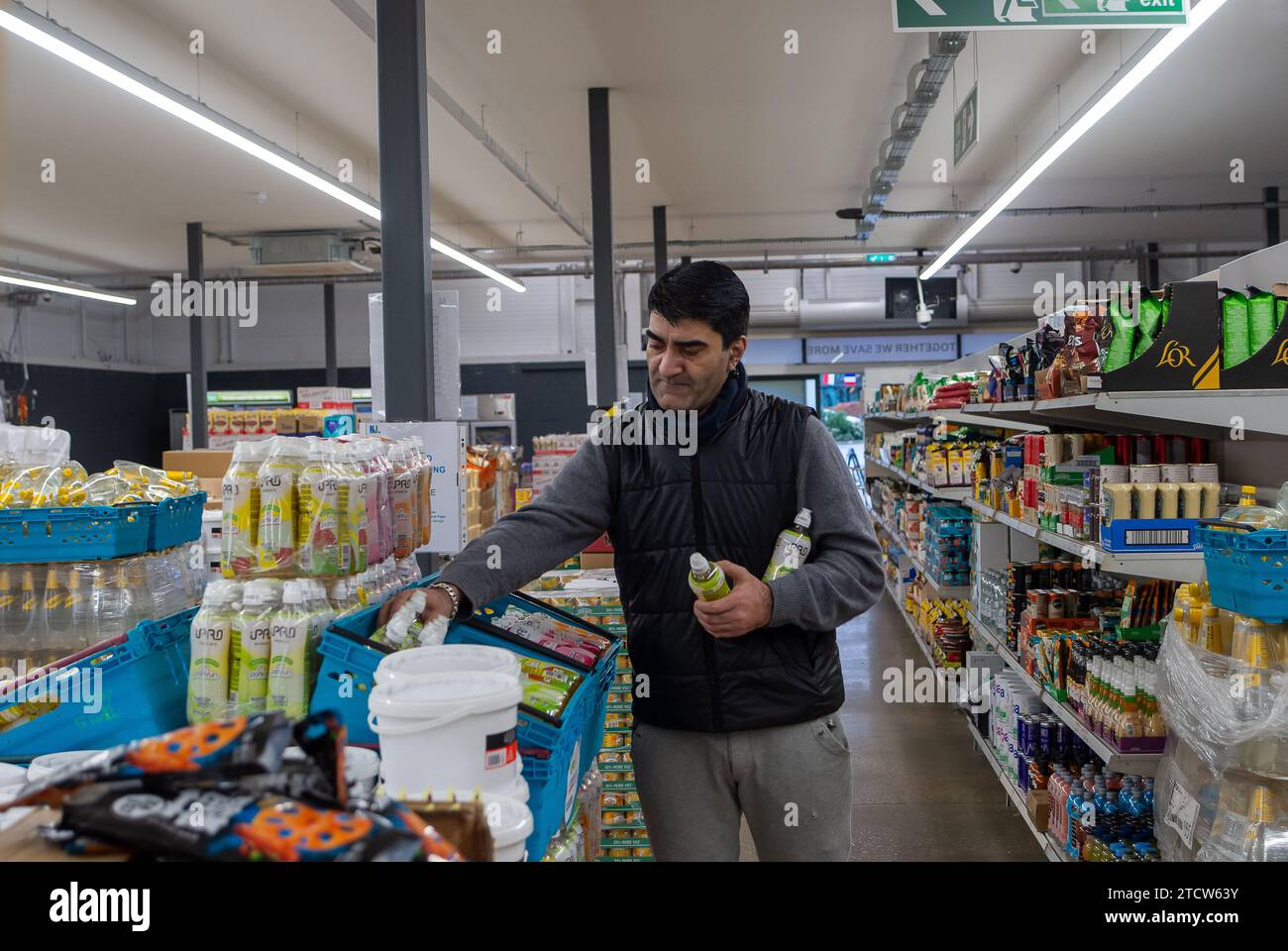 Slough, Regno Unito. 14 dicembre 2023. Volontario Deedar al lavoro. Notjust A Store ha aperto un nuovo grande negozio al Westgate Retail Park sulla A4 a Slough, Berkshire, accanto a Currys. L'enorme negozio vende cibo a prezzi scontati, dove i clienti possono riempire un cestino con articoli a £5 che costerebbero circa £15 altrove. Gran parte del cibo è passato il migliore prima della data o è in eccesso, ma è comunque perfettamente accettabile da consumare. È aperto a tutti coloro che odiano gli sprechi e amano fare affari. Gli acquirenti non devono essere membri per fare acquisti in negozio o avere una soglia di reddito. Credito: Maureen McLean/Alamy Live ne Foto Stock