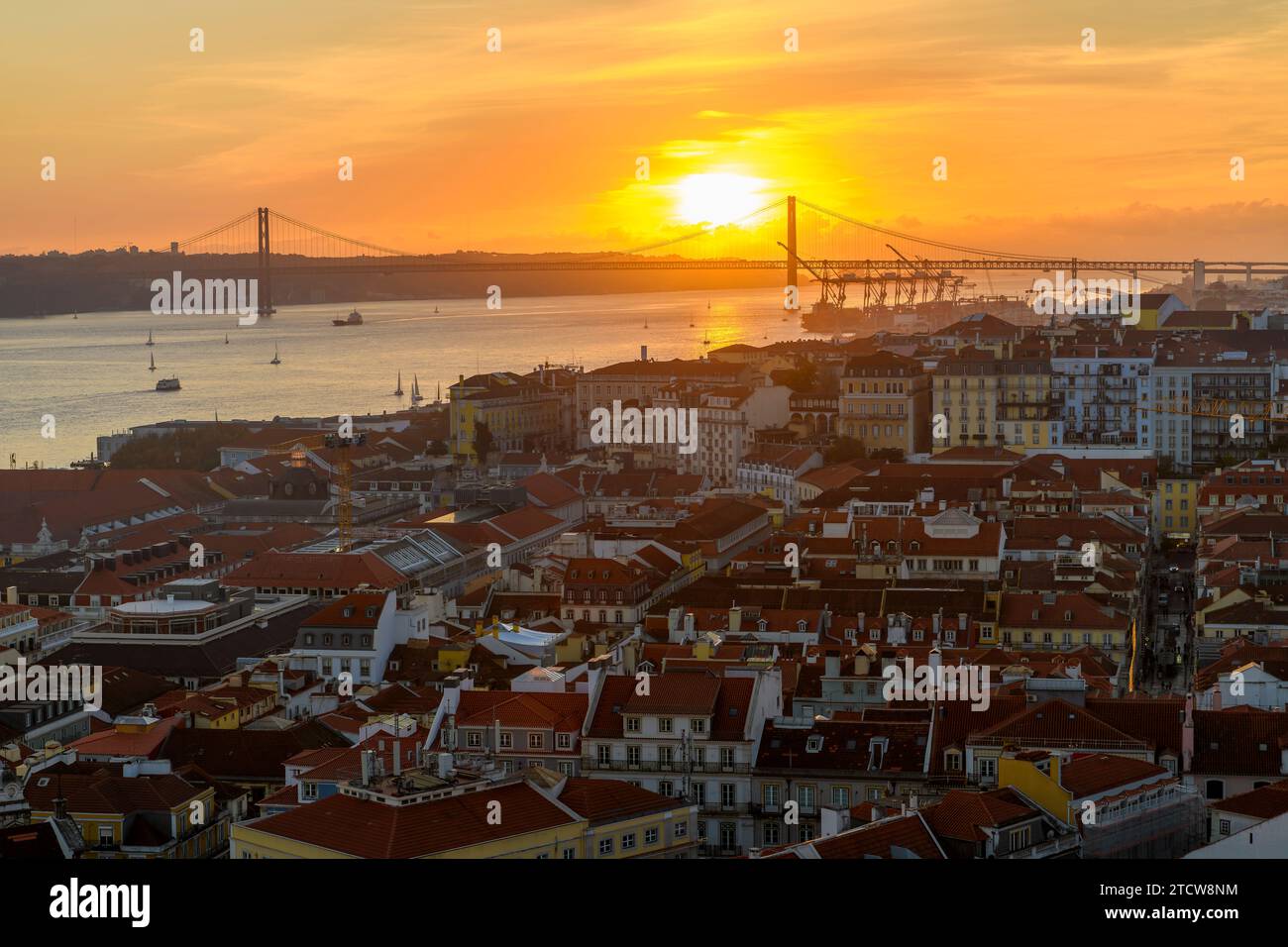 Vista al tramonto del monumento e della statua del Santuario del Cristo Re che si affaccia sul fiume Tago e sul Ponte 25 de Abril dal quartiere di Alfama Foto Stock
