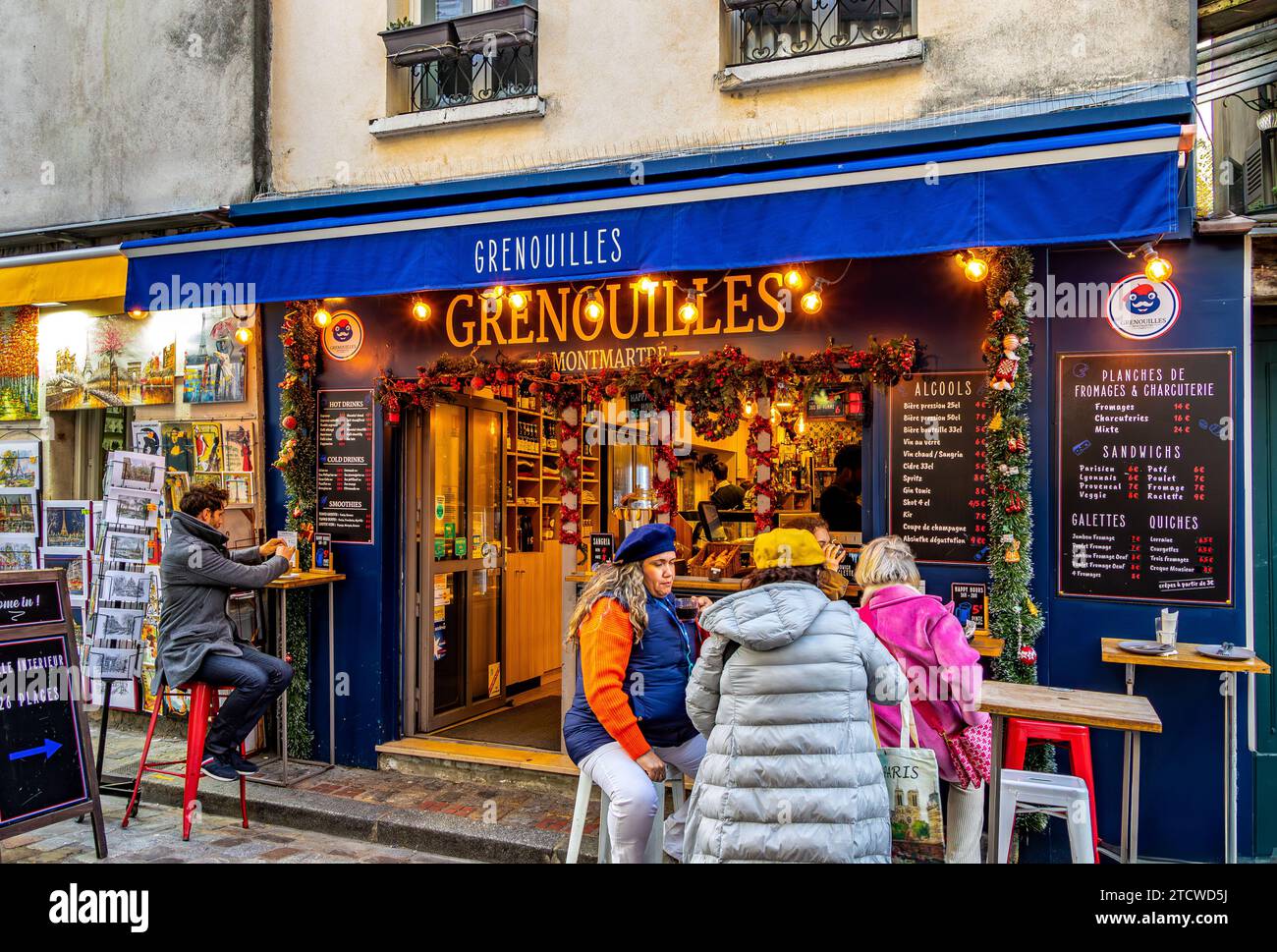 Persone sedute fuori Grenouilles, uno snack bar compatto con un negozio di gastronomia e vino a Montmartre, nel 18° arrondissemnt di Parigi, Francia Foto Stock