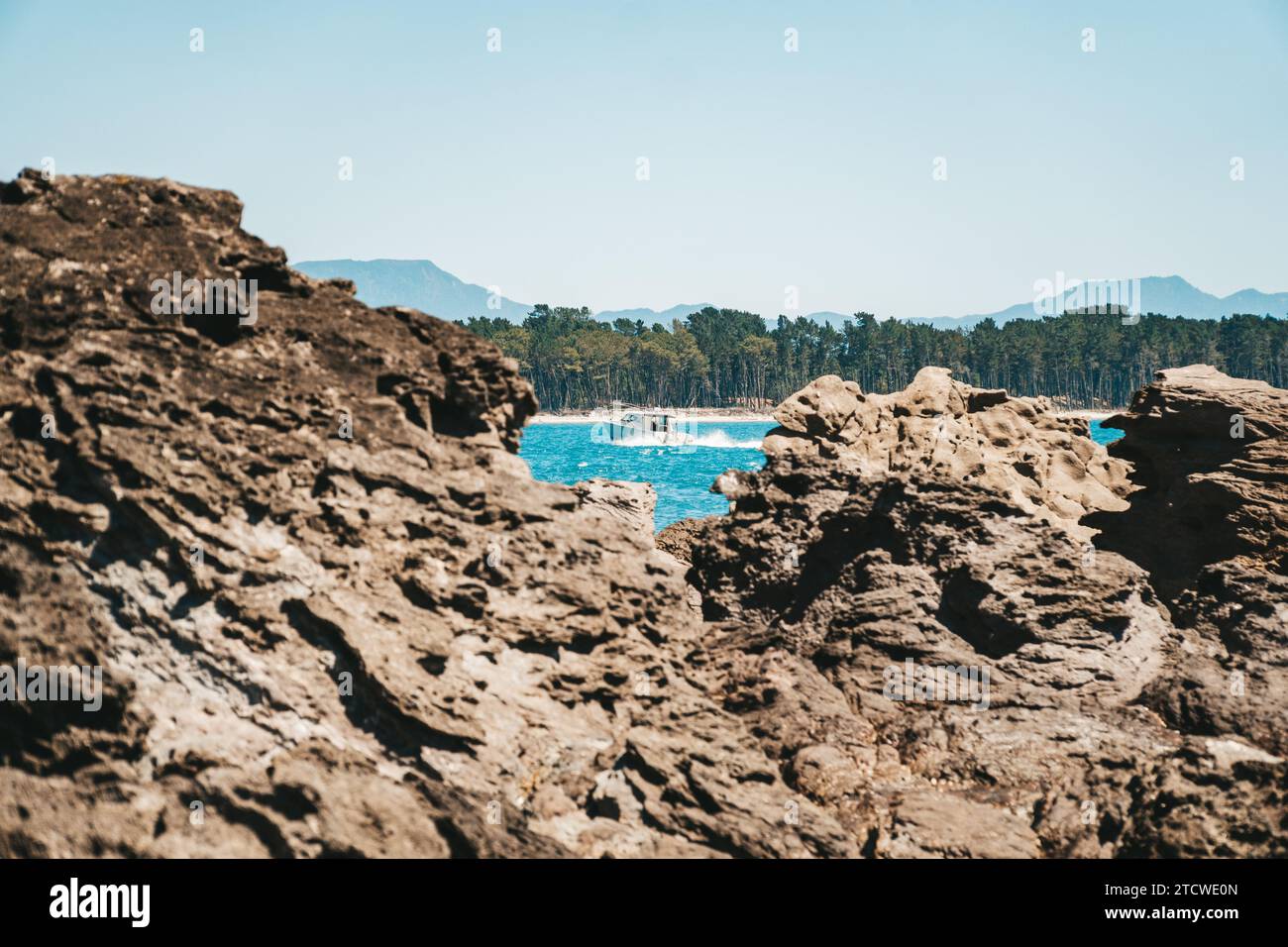 Barca che passa tra le rocce nell'acqua presso la spiaggia del Monte Maunganui, nuova Zelanda. Foto Stock