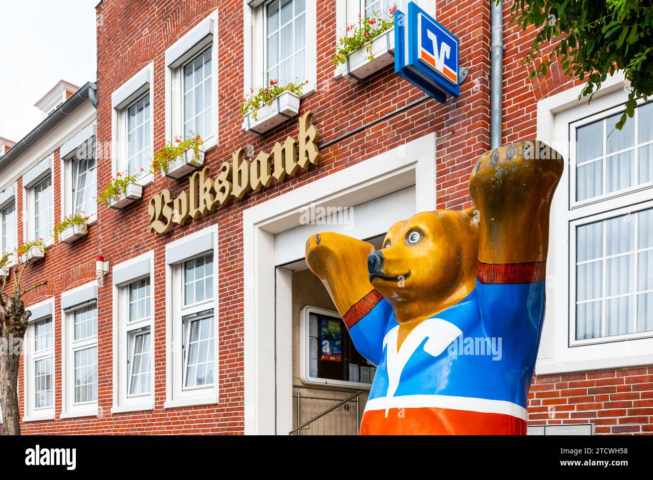 Esens, Germania - 19.09.2023: Facciata in mattoni della Volksbank con logo, lettere e Buddy Bear in primo piano, Esens, AM Markt, Mare del Nord, Germania Foto Stock