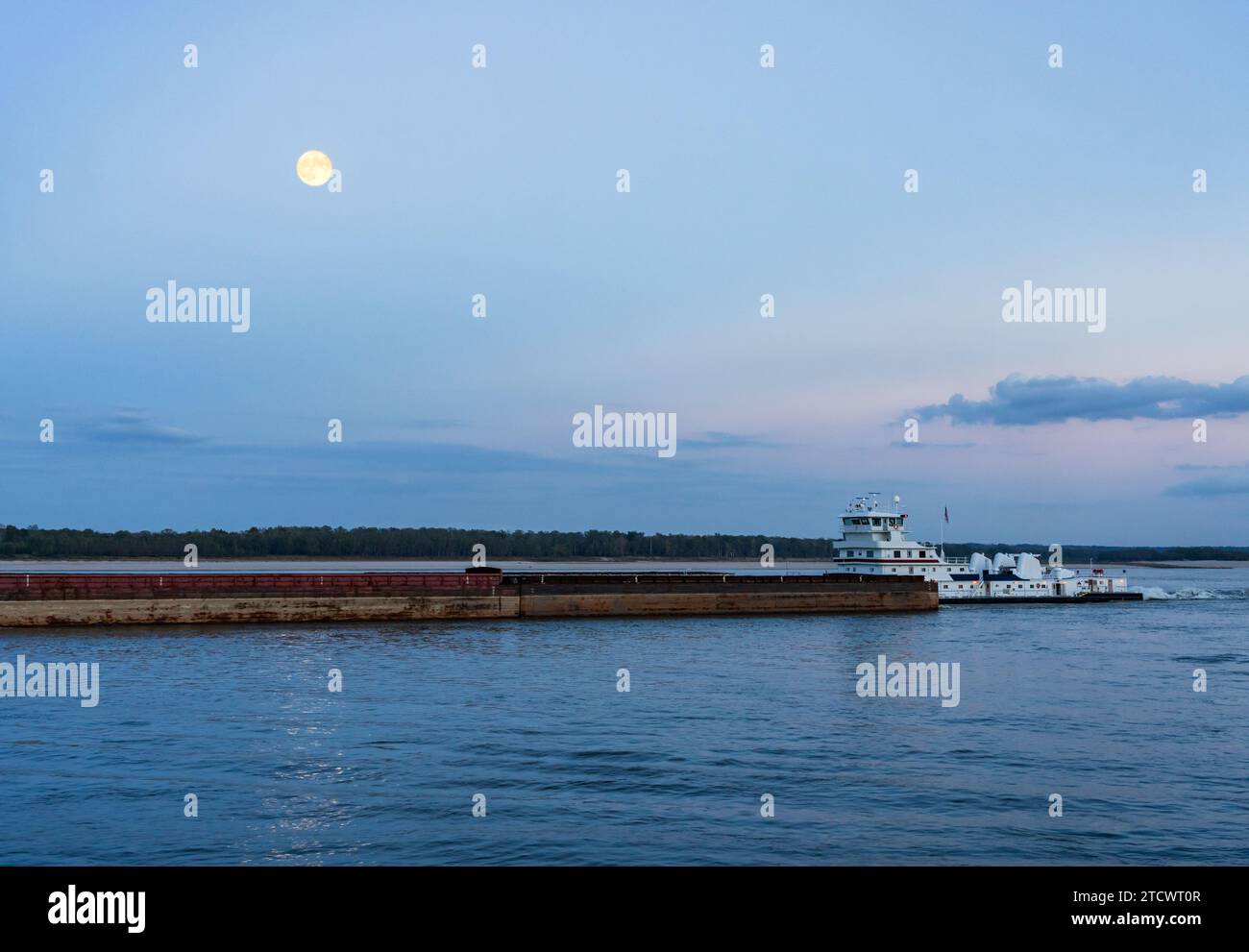 Grande chiatta fluviale carica di grano che naviga lungo il fiume Mississippi vicino a Natchez al crepuscolo Foto Stock