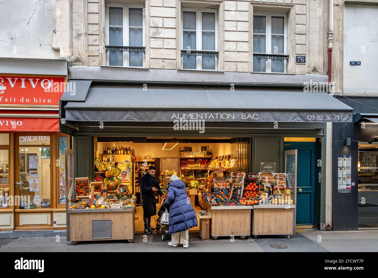 Una signora che entra in Alimentation BAC , un negozio di frutta e verdura in Rue du Bac nel 7° arrondissement di Parigi , Francia Foto Stock