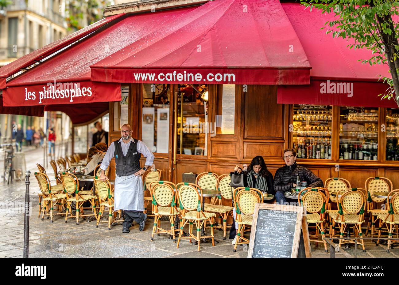 Un cameriere che si trova all'esterno di Les Philosophes, un ristorante francese, un bistro situato nell'area Marais di Parigi, Francia Foto Stock