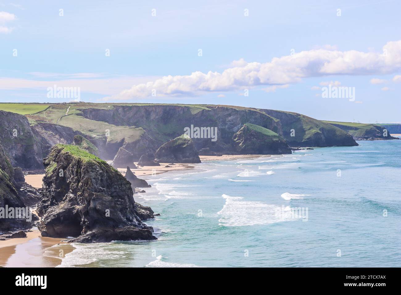 Bedruthan Steps, Cornovaglia, con la bassa marea sotto il sole, contro un cielo azzurro Foto Stock