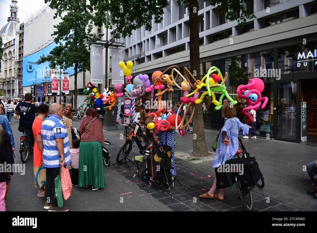 Uomo vestito con abito da clown che crea e vende animali palloncini nella via dello shopping Meir nel centro della città di Anversa Foto Stock