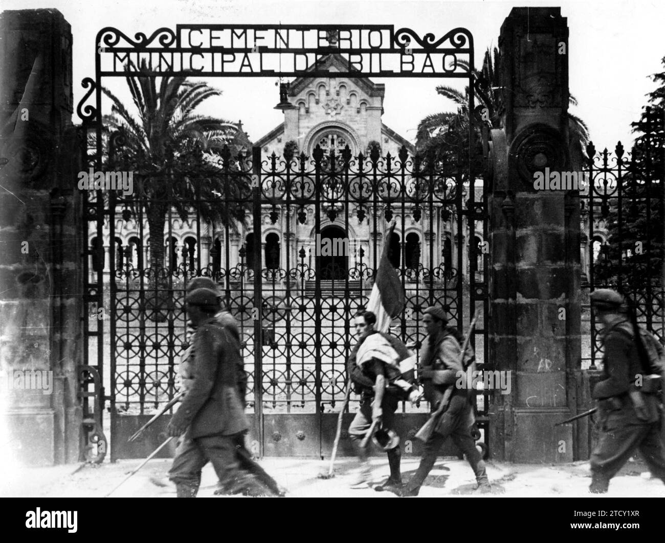 06/30/1937. Un soldato, che passa di fronte al Cimitero, porta una bandiera il cui bastone è un bastone, da collocare in qualche luogo conquistato. Didascalia foto originale: 'Sulla traforatura di questa recinzione di pessimo gusto la figura eternamente bella del soldato con una bandiera con un bastone rustico. Non è la bandiera dell'unità. È una bandiera, probabilmente fatta dalle ragazze di una città liberata; quella bandiera è quella che viene posta, a rischio della vita, nelle posizioni o nelle città al momento della conquista. Quella bandiera che fa tanto bene a coloro che la sognano per mesi. Credito: Album / Arc Foto Stock