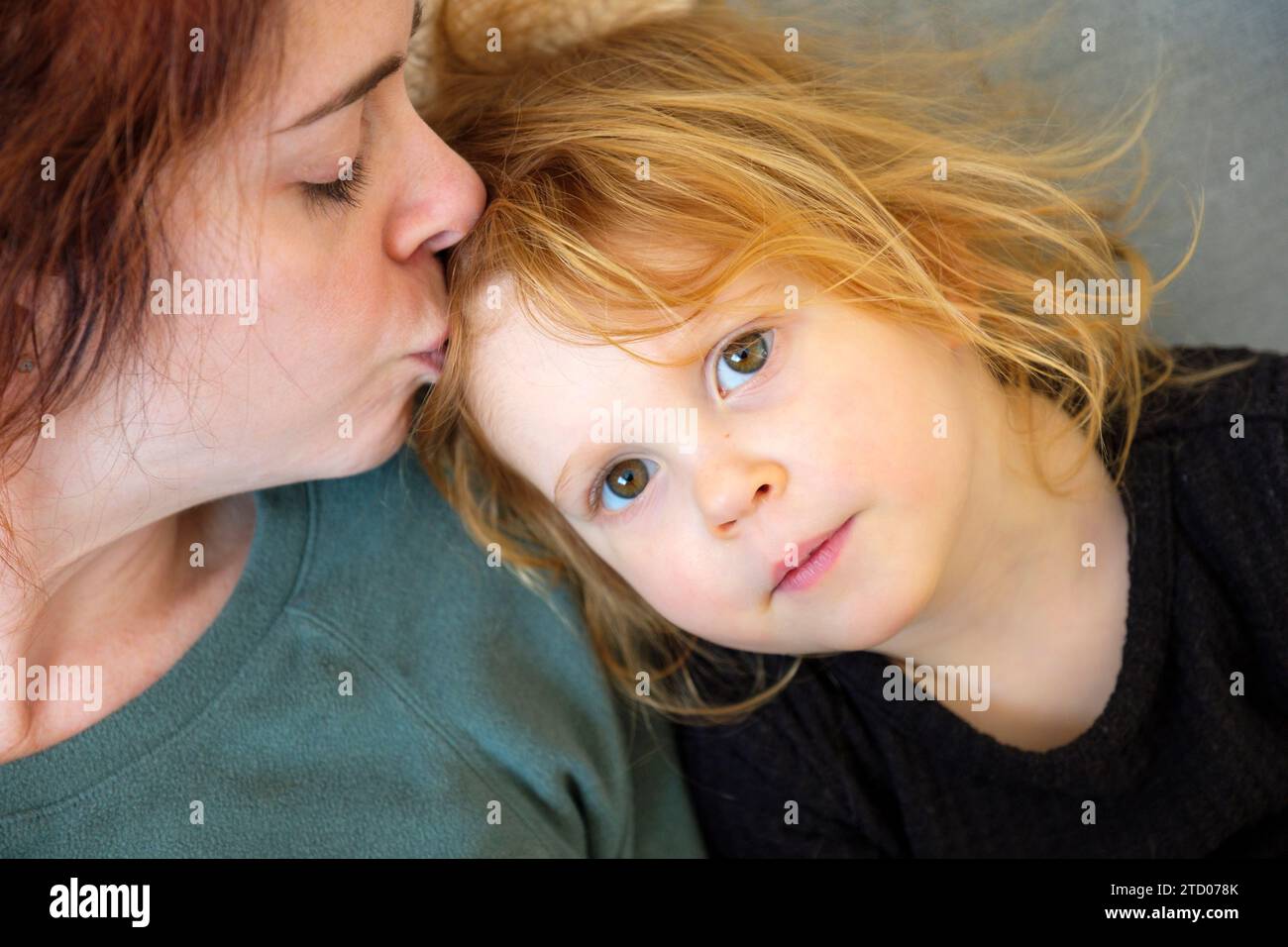Madre amorevole che abbraccia la figlia rossa con emozione positiva Foto Stock