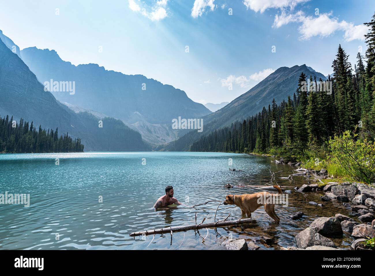 Escursionista che gioca con il Dog Lakeside del lago alpino Foto Stock