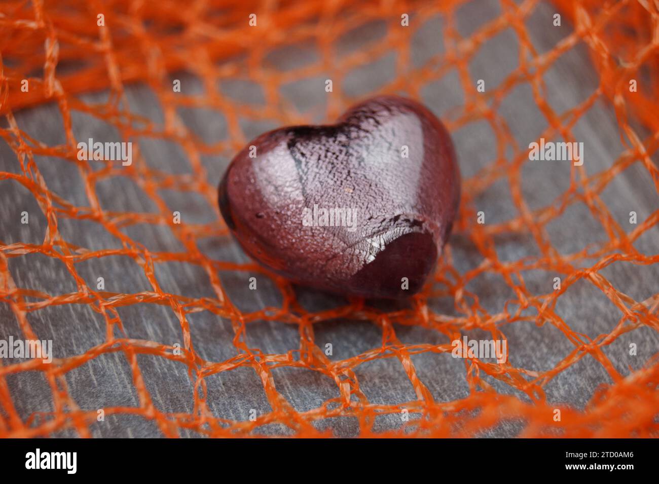 cuore di vetro rosso su una rete Foto Stock