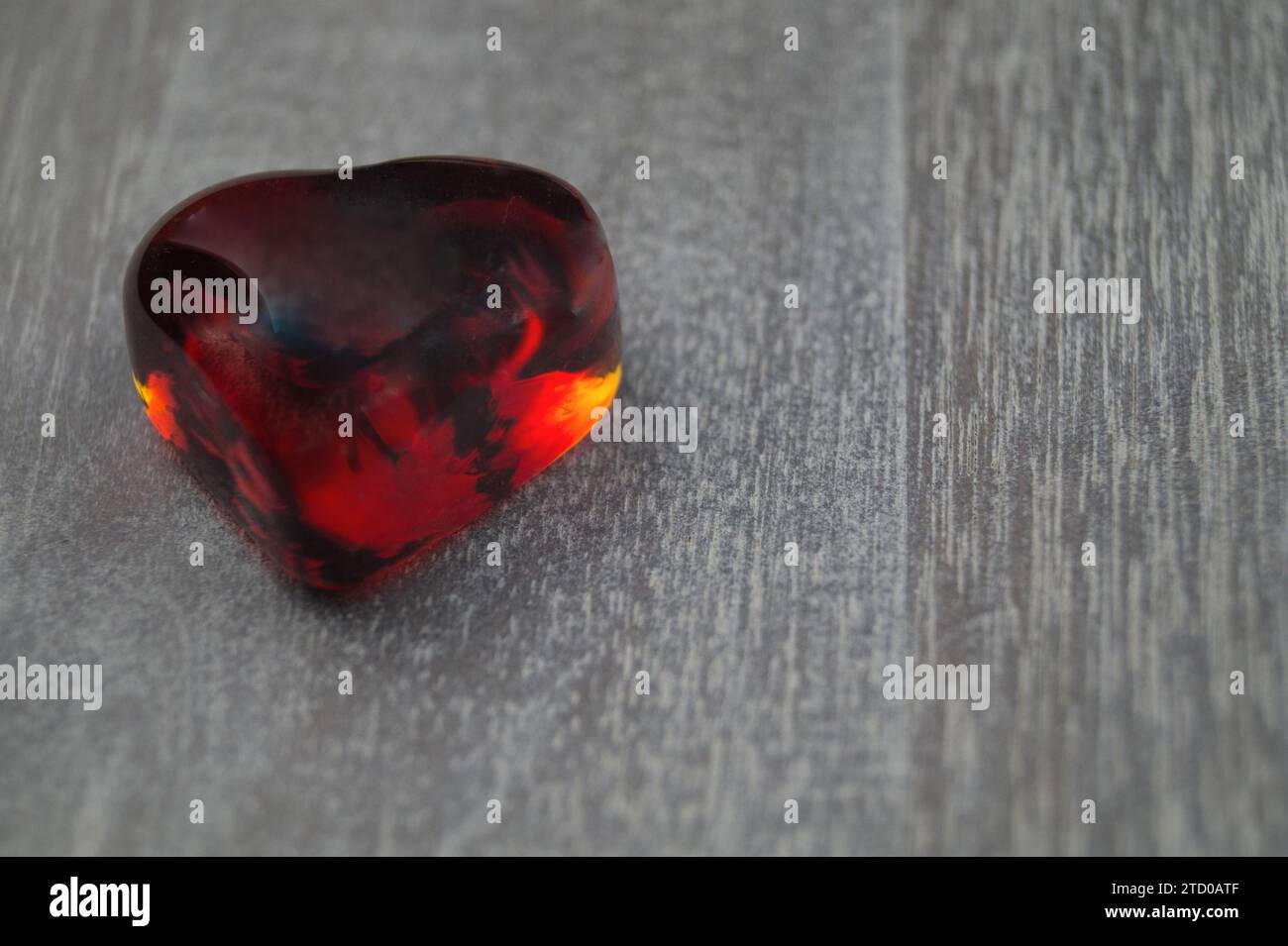 cuore di vetro rosso su legno Foto Stock