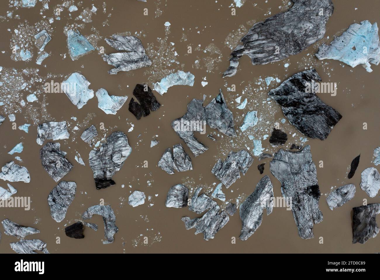 Colpo d'aria che cattura frammenti di ghiaccio nelle acque glaciali di un bacino fluviale islandese, raffigurando un mosaico naturale Foto Stock