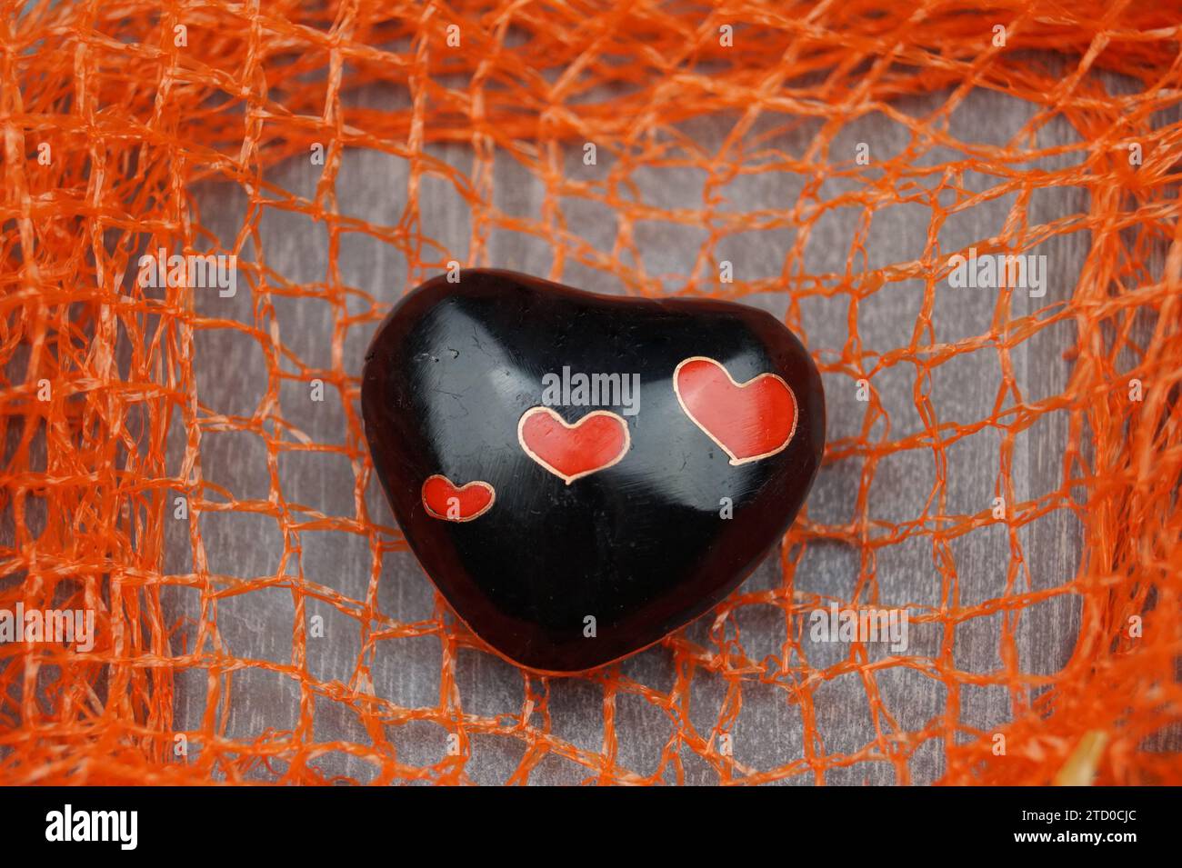 cuore nero con piccoli cuori rossi su una rete Foto Stock