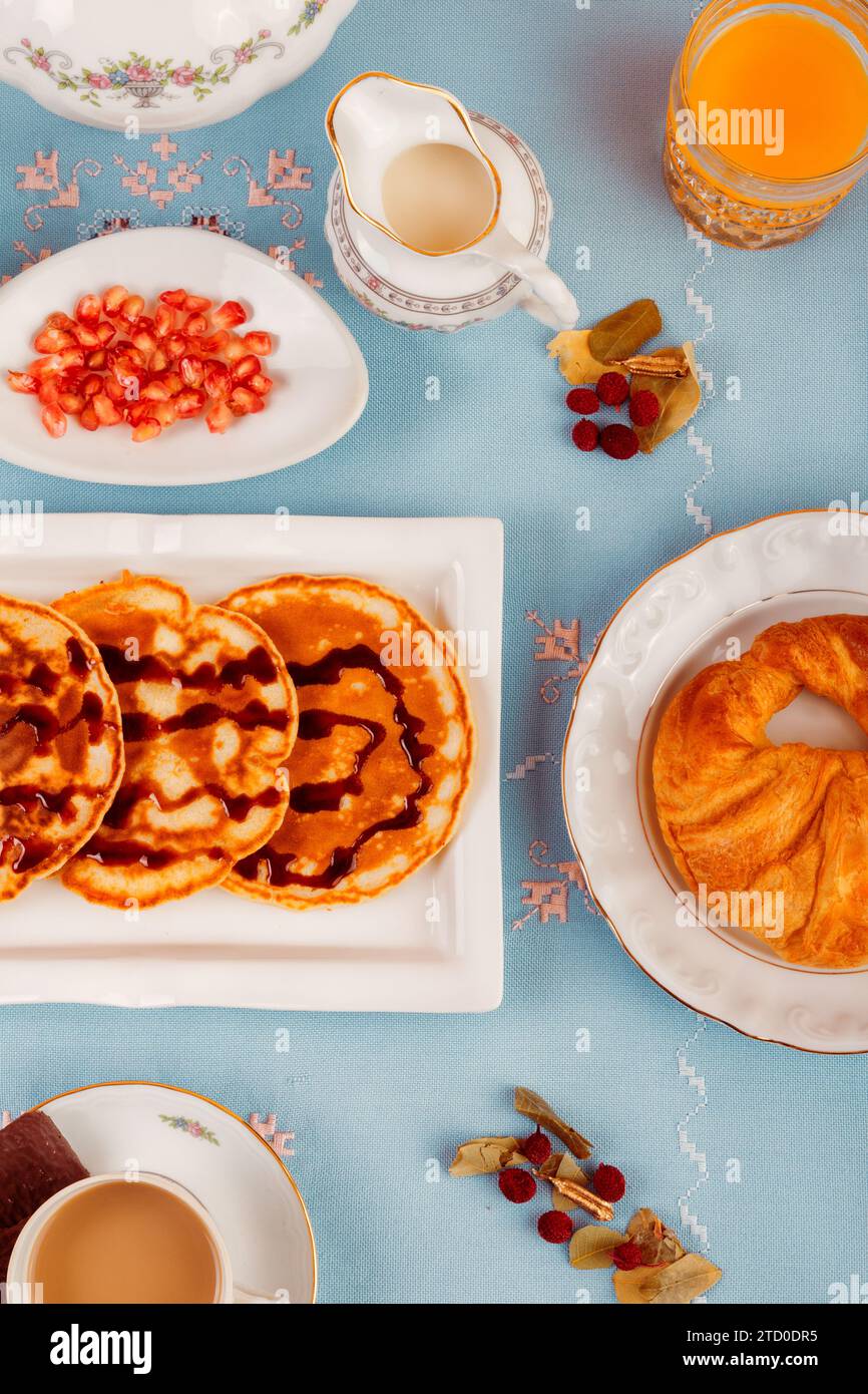 Una varietà di cibi per la colazione, con waffle, frutta e bevande, su uno sfondo blu vibrante. Foto Stock
