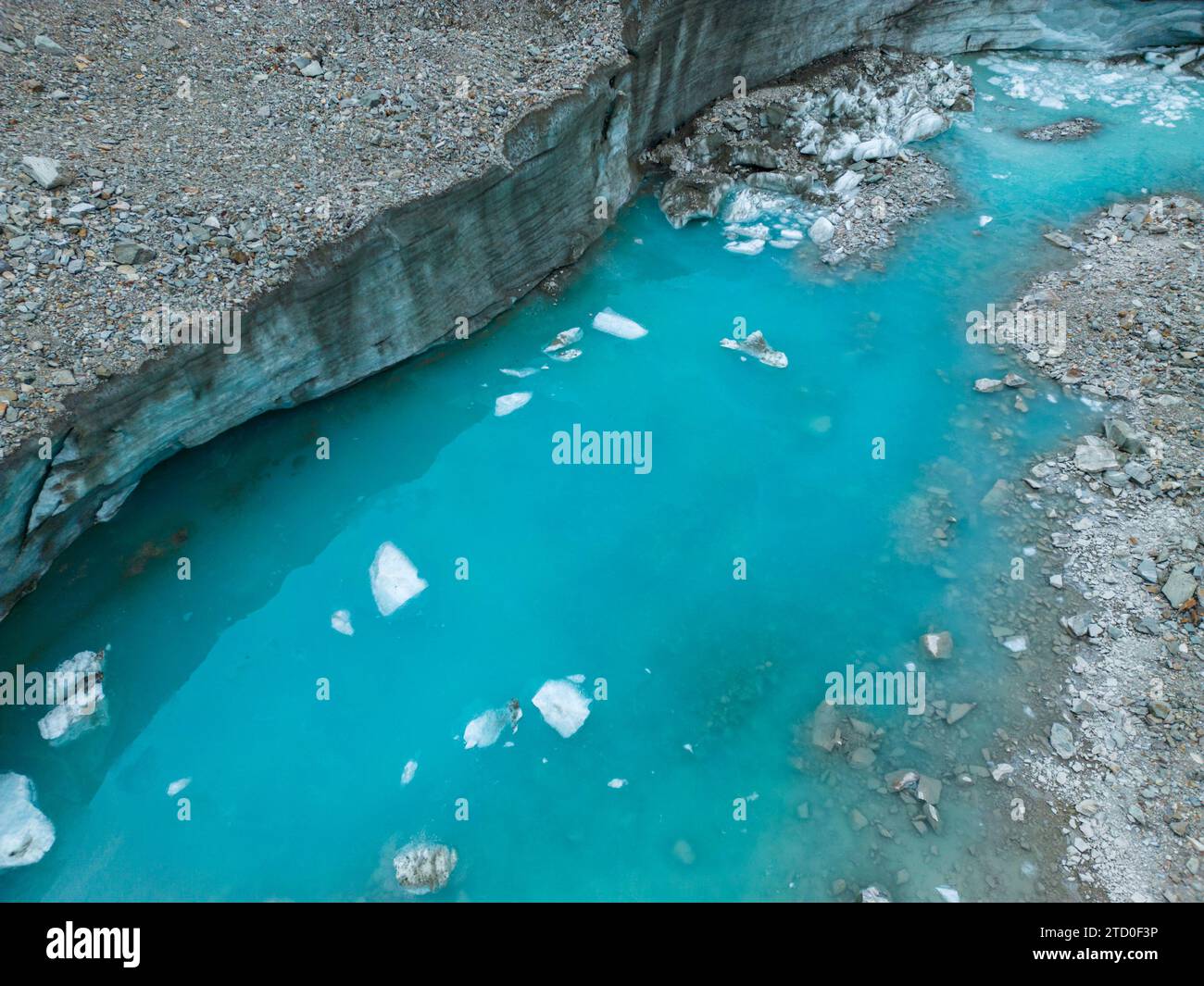 Un vivace fiume glaciale turchese scorre attraverso un paesaggio roccioso con blocchi di ghiaccio sparsi lungo la superficie dell'acqua. Foto Stock