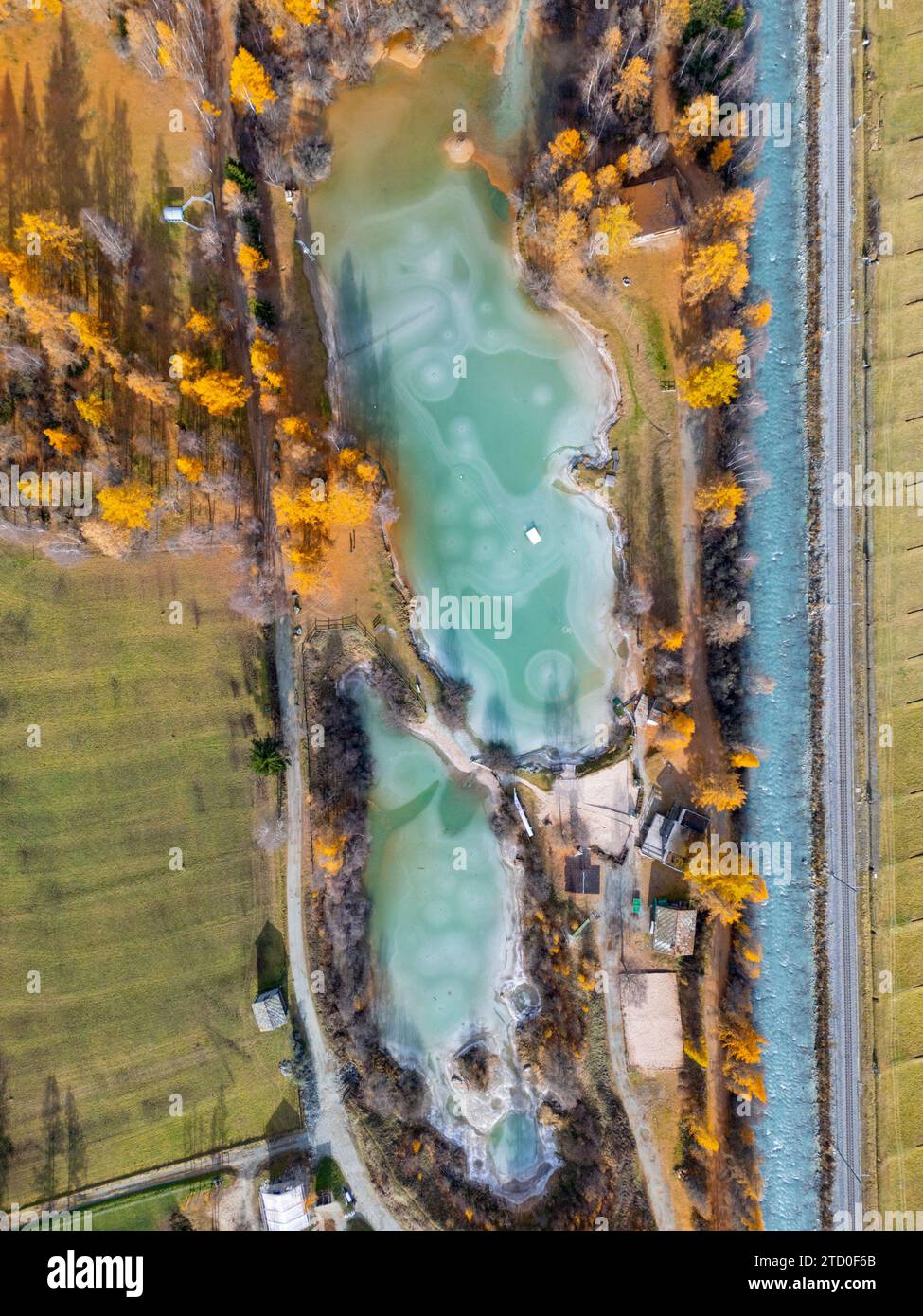 Incredibile ripresa aerea che cattura la bellezza serena di un fiume turchese che si snoda attraverso una vibrante valle svizzera adornata di colori autunnali Foto Stock