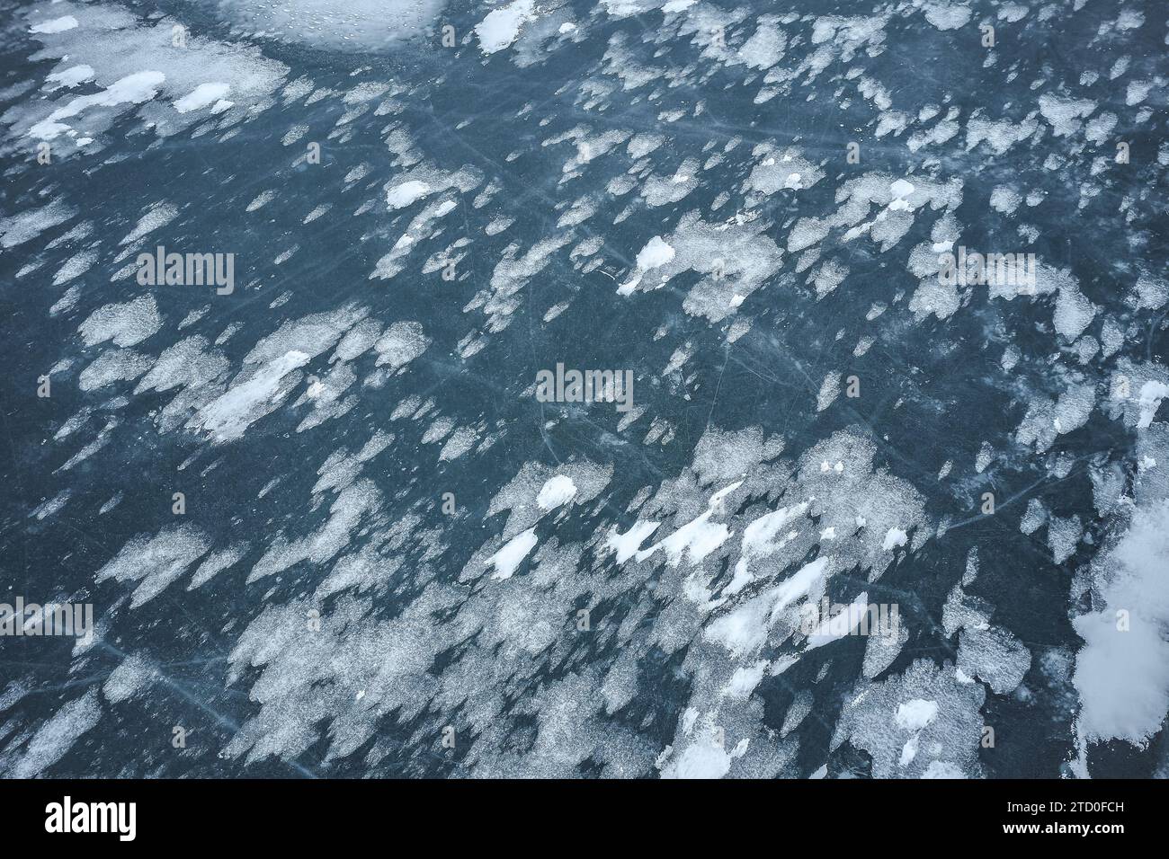 Un'immagine ad alta risoluzione che cattura gli intricati dettagli di un lago ghiacciato, macchiato di neve e ghiaccio. Foto Stock