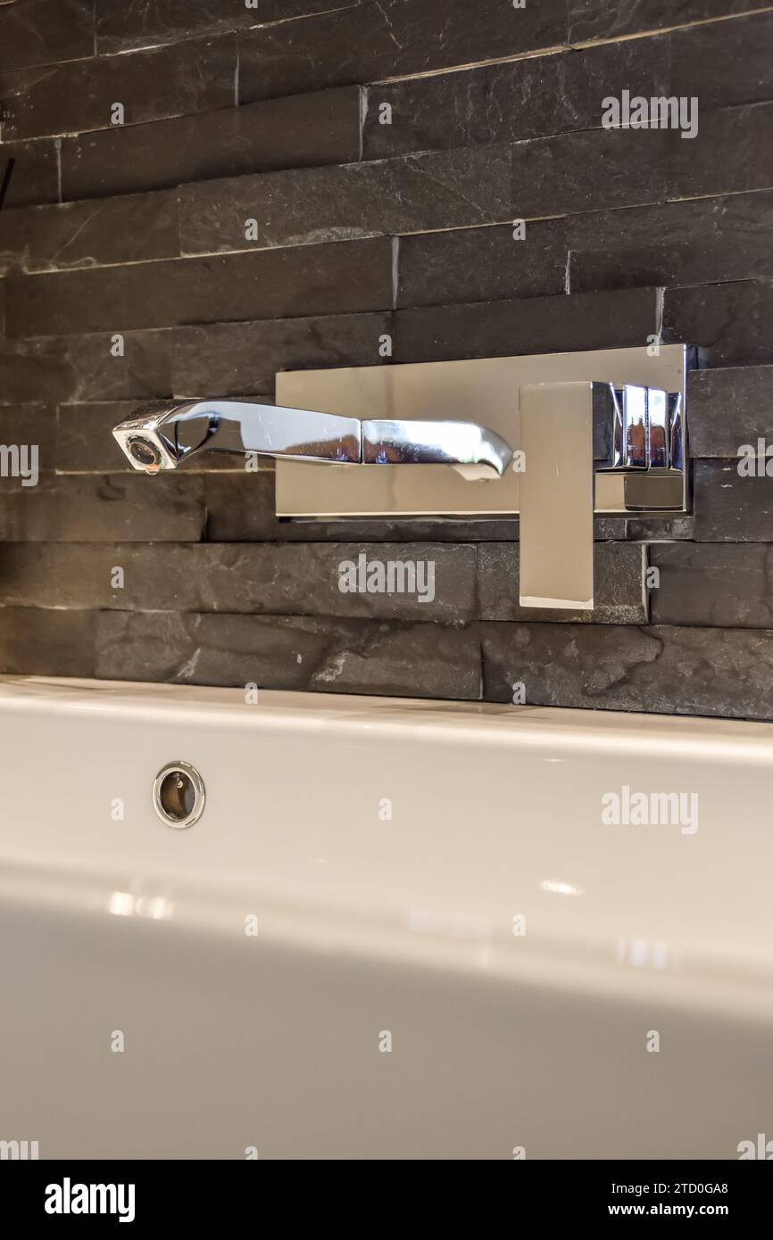 Rubinetto in acciaio inox montato a parete su lavabo in ceramica bianca nel lussuoso bagno dell'appartamento Foto Stock
