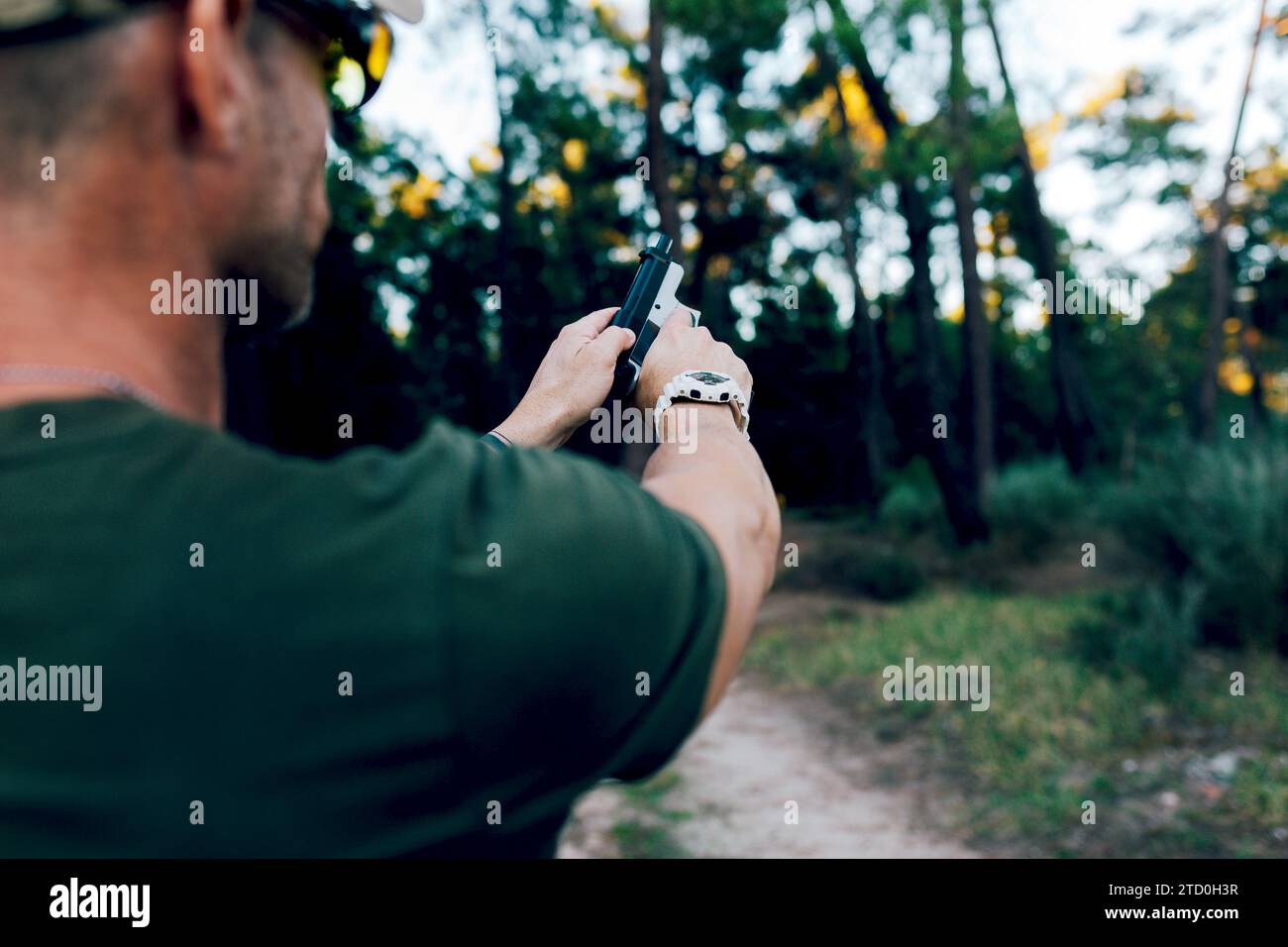 Coltiva il commando militare della forza speciale di mezza età irriconoscibile che pratica il tiro al bersaglio con la pistola nella foresta al tramonto Foto Stock